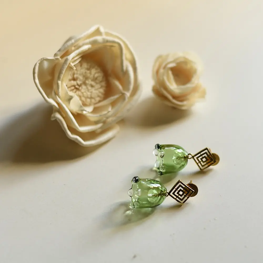 handcrafted sage green glass drop earrings featuring a bell blossom and orb dangle with brass geometric stud tops