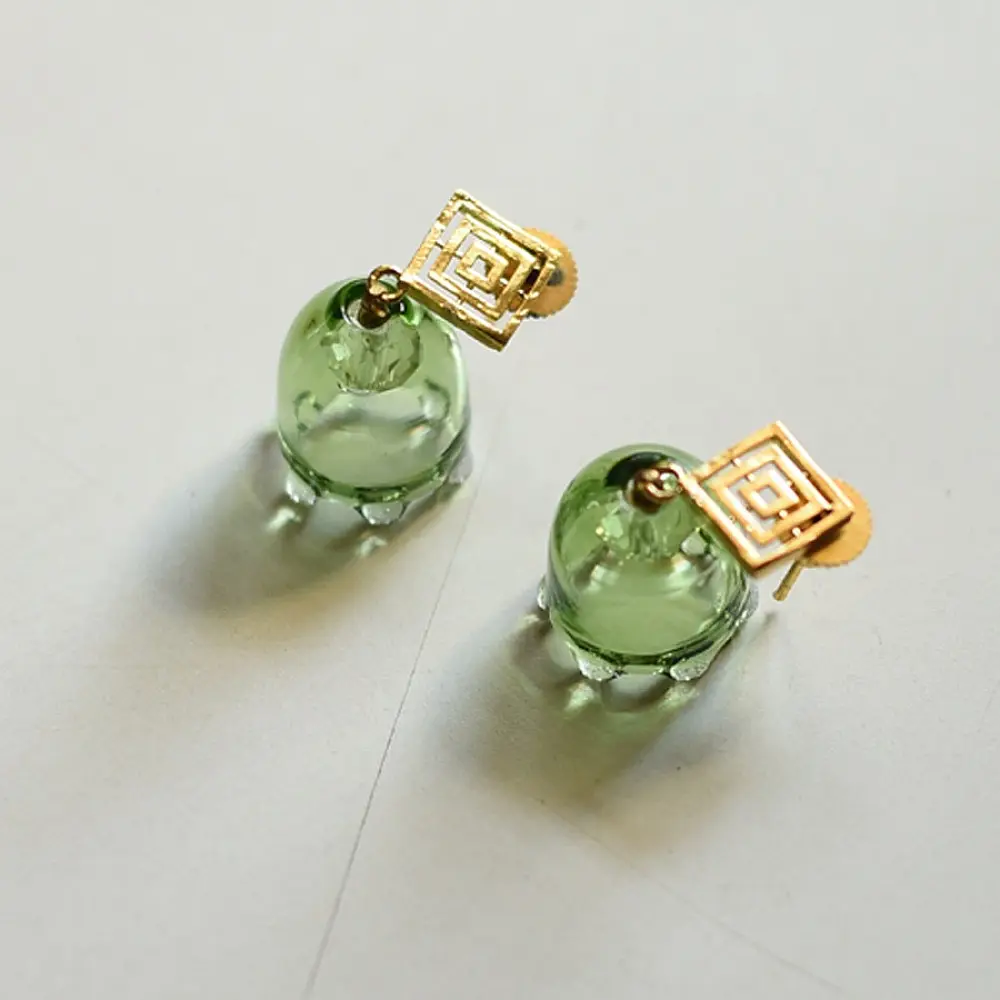 handcrafted sage green glass drop earrings featuring a bell blossom and orb dangle with brass geometric stud tops