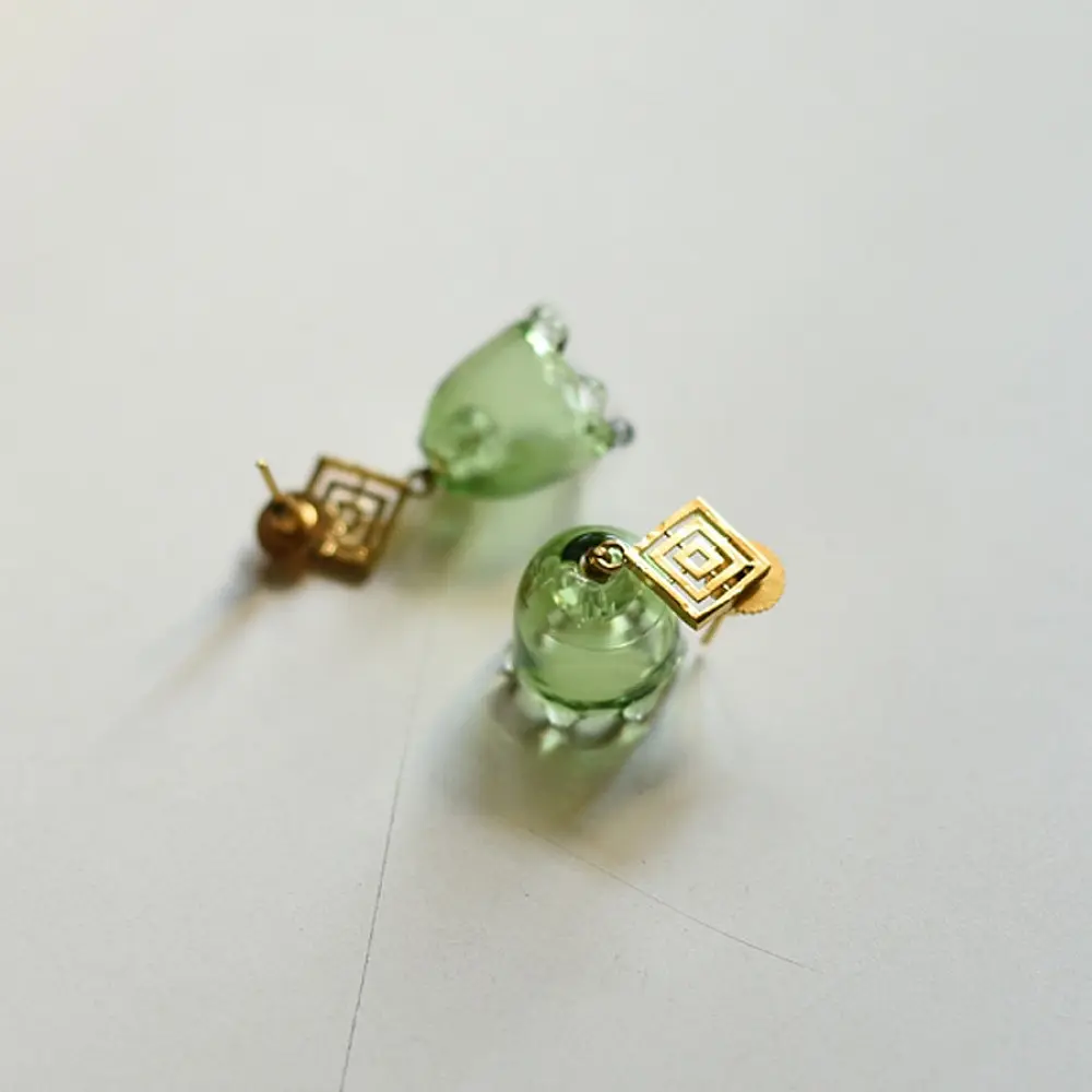 handcrafted sage green glass drop earrings featuring a bell blossom and orb dangle with brass geometric stud tops