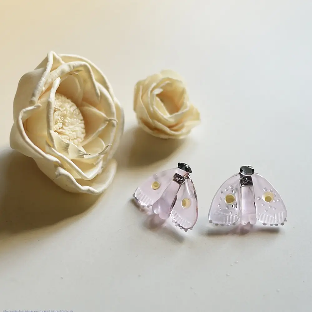 handcrafted translucent pale pink glass moth stud earrings featuring textured grooved wings and yellow spot accents