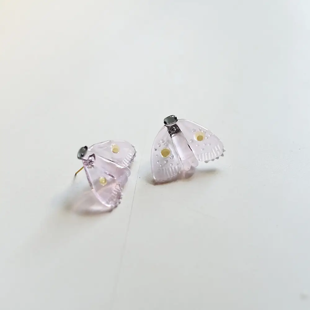 handcrafted translucent pale pink glass moth stud earrings featuring textured grooved wings and yellow spot accents