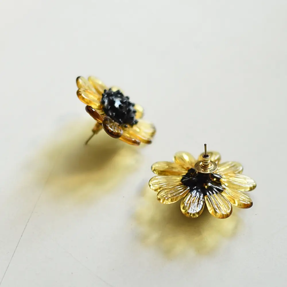 handcrafted translucent amber yellow glass bloom stud earrings with a dark textured center cap on brass post backs