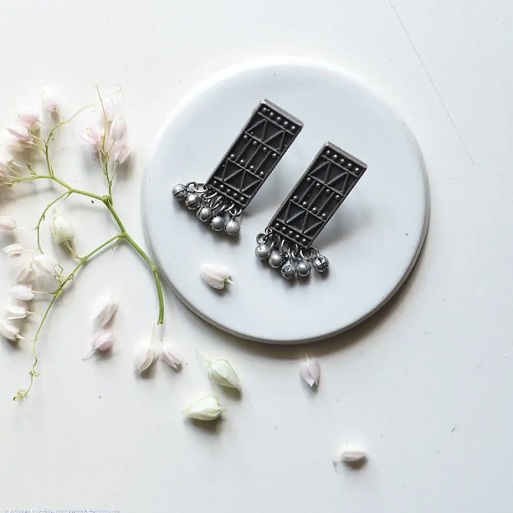handcrafted german silver geometric rectangular drop earrings featuring woven triangular lattice cutouts, textured stud top, and dangling ghungroo bead cluster