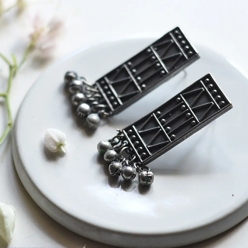 handcrafted german silver geometric rectangular drop earrings featuring woven triangular lattice cutouts, textured stud top, and dangling ghungroo bead cluster