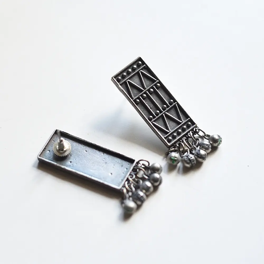 handcrafted german silver geometric rectangular drop earrings featuring woven triangular lattice cutouts, textured stud top, and dangling ghungroo bead cluster