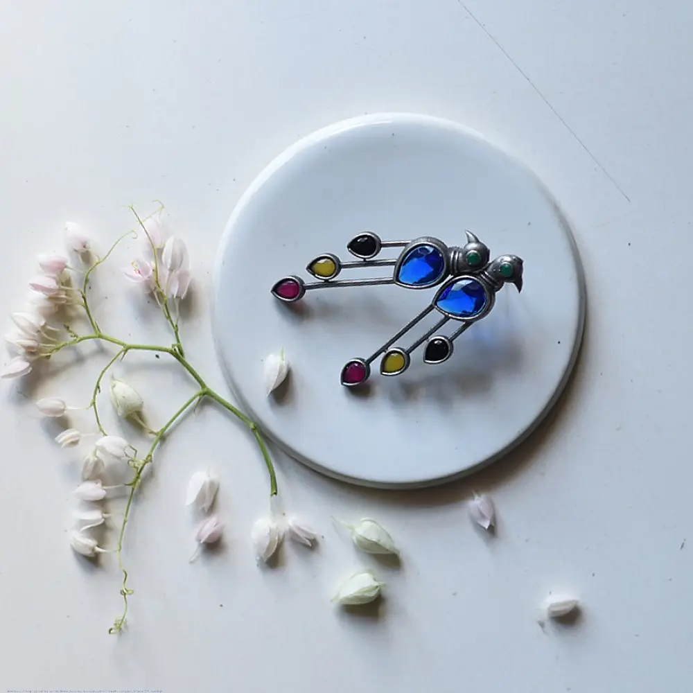 handcrafted german silver bird stud earrings featuring a cobalt blue stone body, jewel-toned glass inlays, and dangling ruby red teardrop tail accent