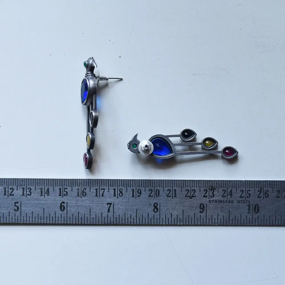 handcrafted german silver bird stud earrings featuring a cobalt blue stone body, jewel-toned glass inlays, and dangling ruby red teardrop tail accent