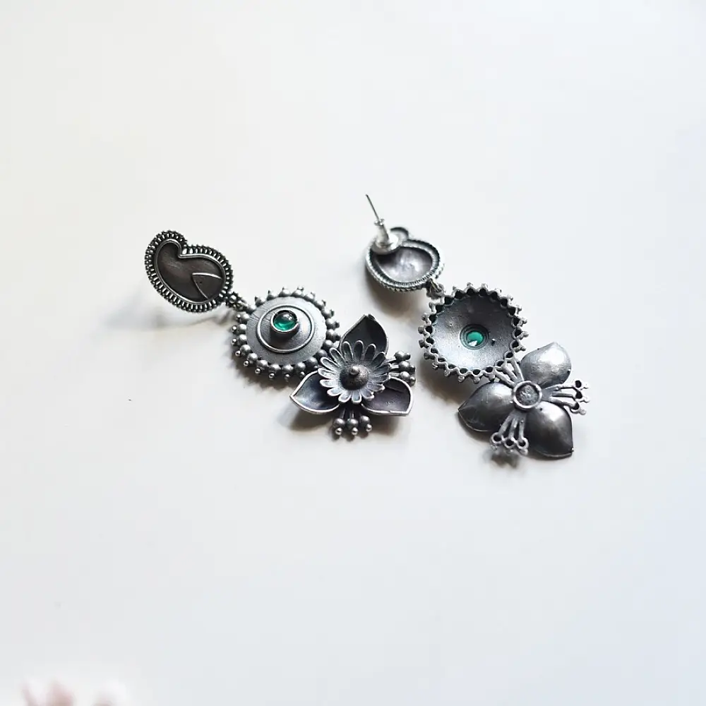 handcrafted german silver drop earrings featuring a textured flower top with emerald green stone inlay and an inverted lotus leaf pendant
