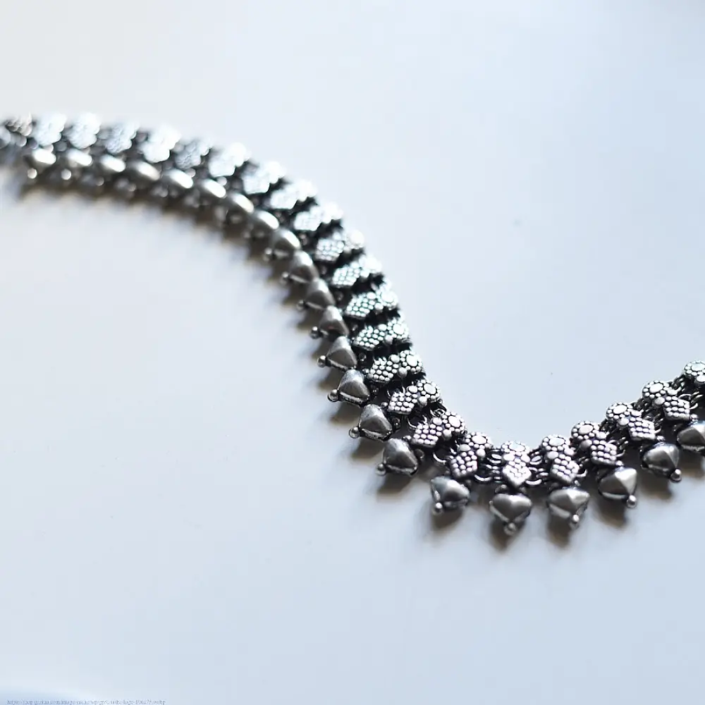 handcrafted german silver choker necklace featuring a central row of textured pyramid spike units, beaded borders, and dangling ghungroo clusters