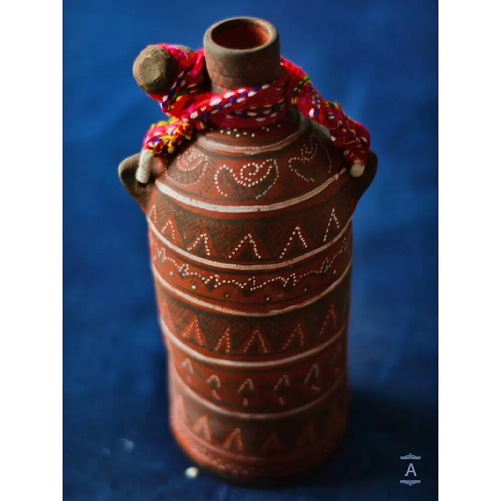 terracotta water bottle with white hand-painted geometric motifs and multicolour cord wrapped neck