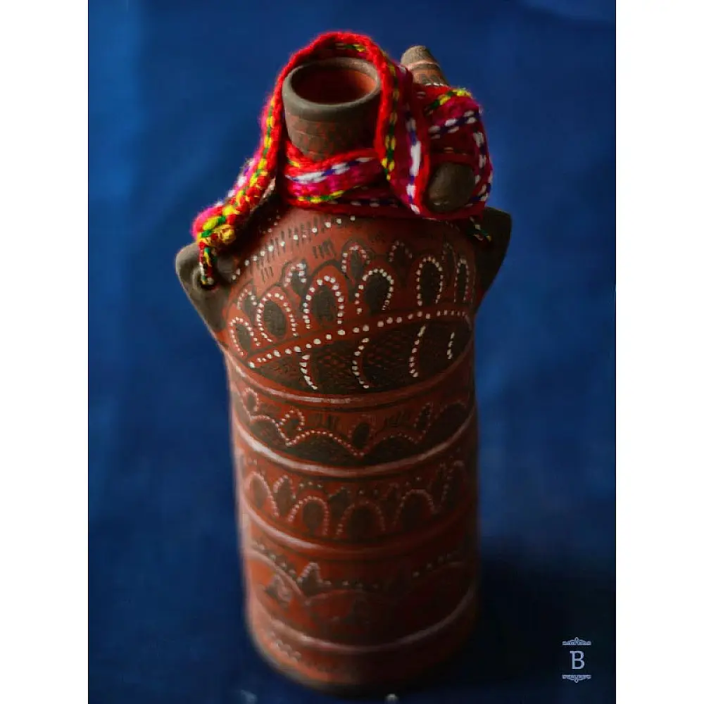 terracotta water bottle with white hand-painted geometric motifs and multicolour cord wrapped neck