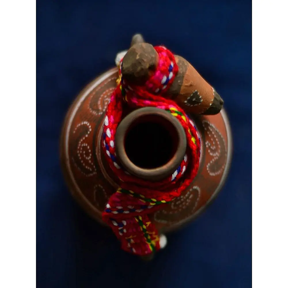 terracotta water bottle with white hand-painted geometric motifs and multicolour cord wrapped neck