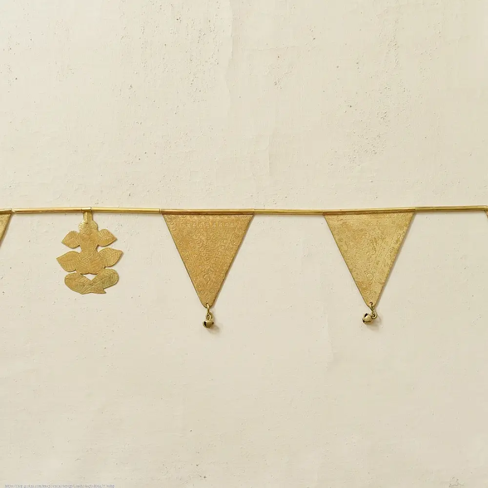 handmade brass triangle design toran door hanging featuring pennant shaped brass flags linked on a brass chain with central floral pendant drop   