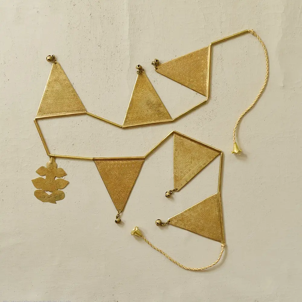 handmade brass triangle design toran door hanging featuring pennant shaped brass flags linked on a brass chain with central floral pendant drop   
