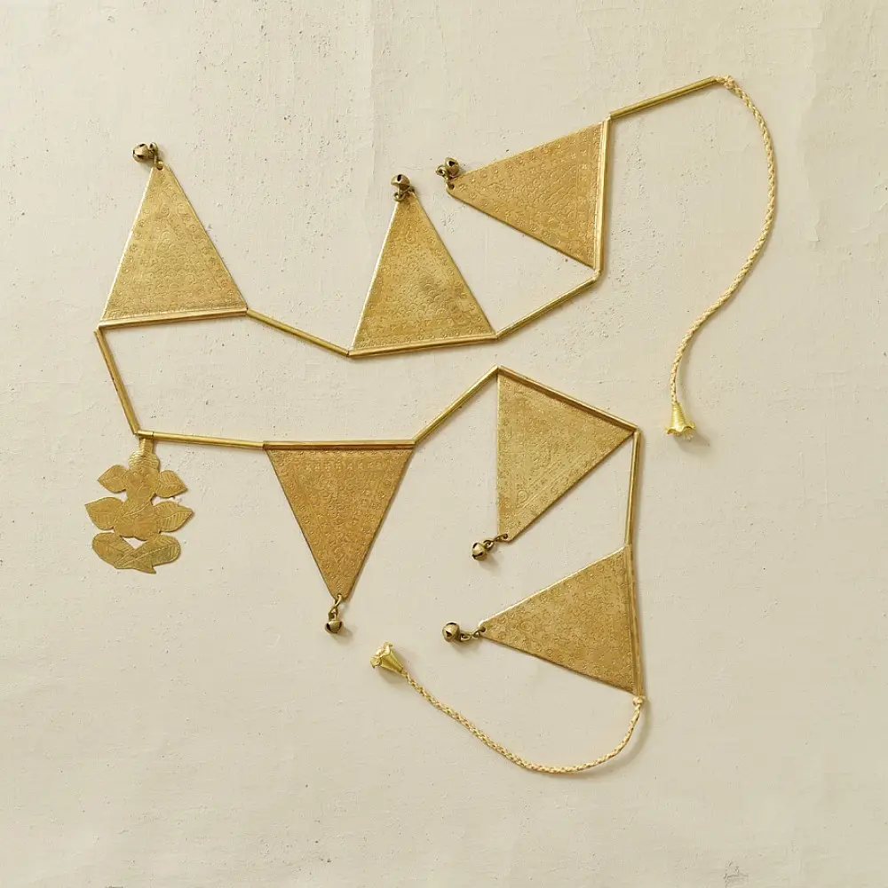 handmade brass triangle design toran door hanging featuring pennant shaped brass flags linked on a brass chain with central floral pendant drop   