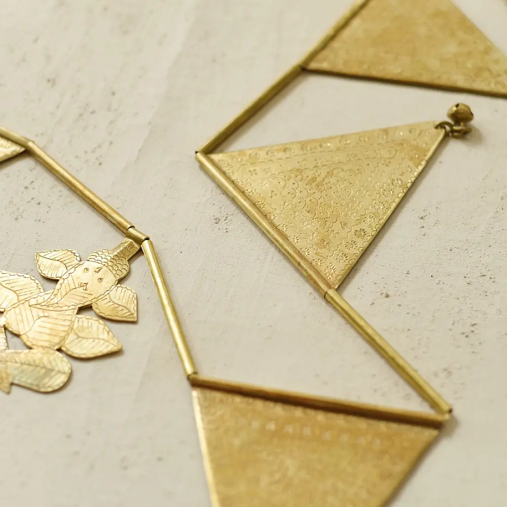 handmade brass triangle design toran door hanging featuring pennant shaped brass flags linked on a brass chain with central floral pendant drop   