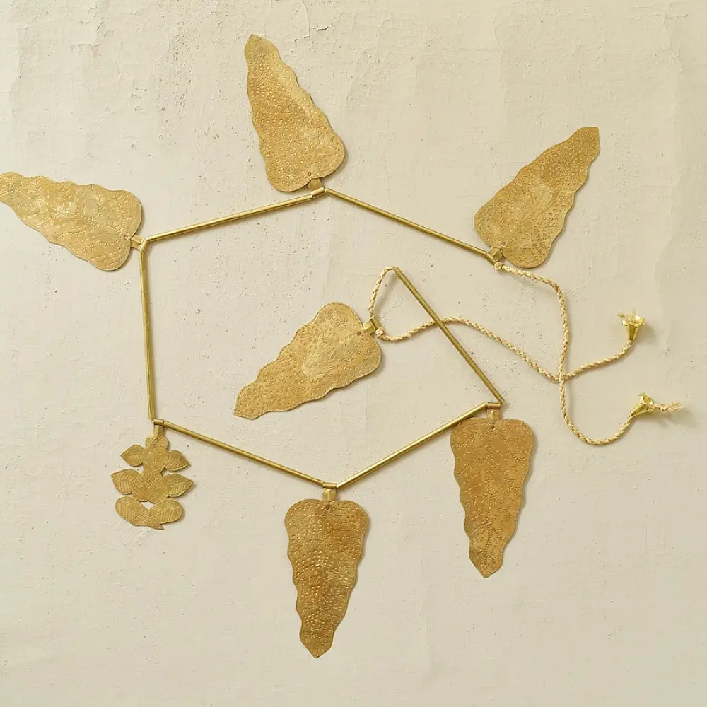 handmade brass leaf design toran door hanging featuring mango leaf shaped brass plates linked on a brass chain with central floral pendant