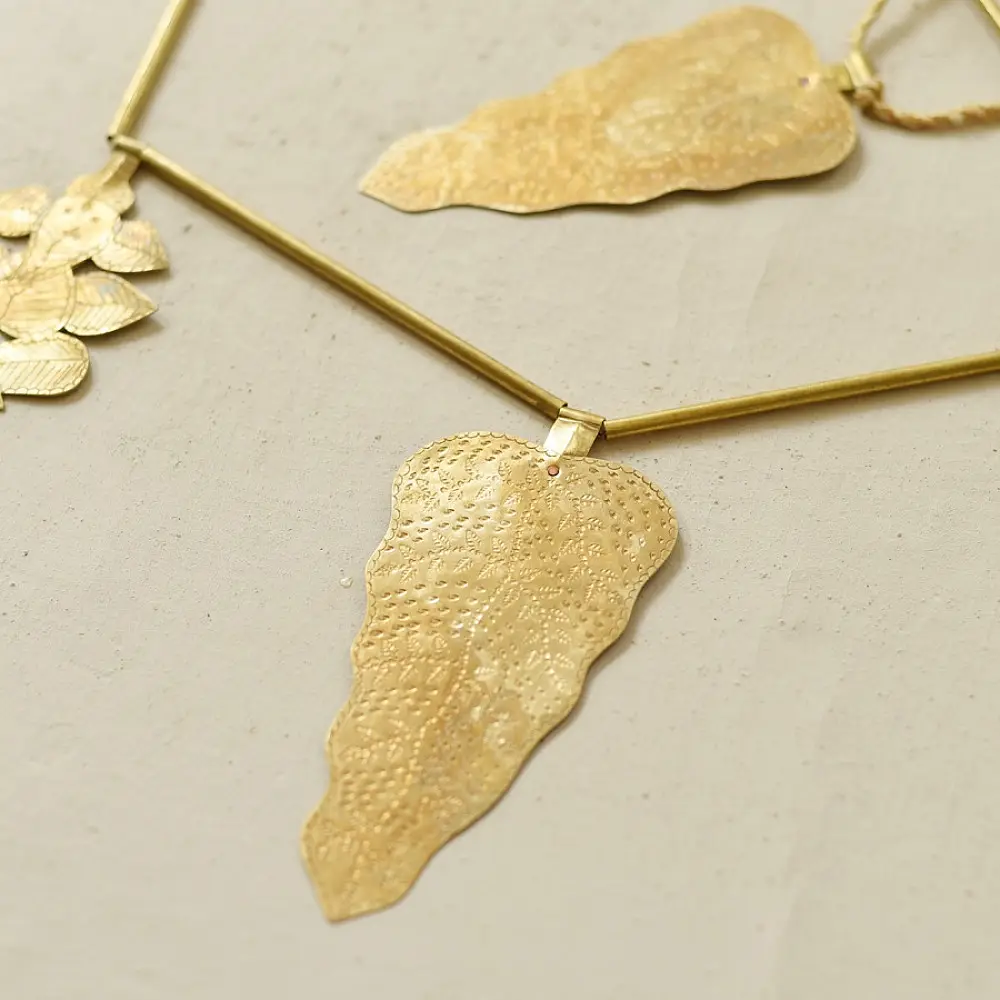 handmade brass leaf design toran door hanging featuring mango leaf shaped brass plates linked on a brass chain with central floral pendant