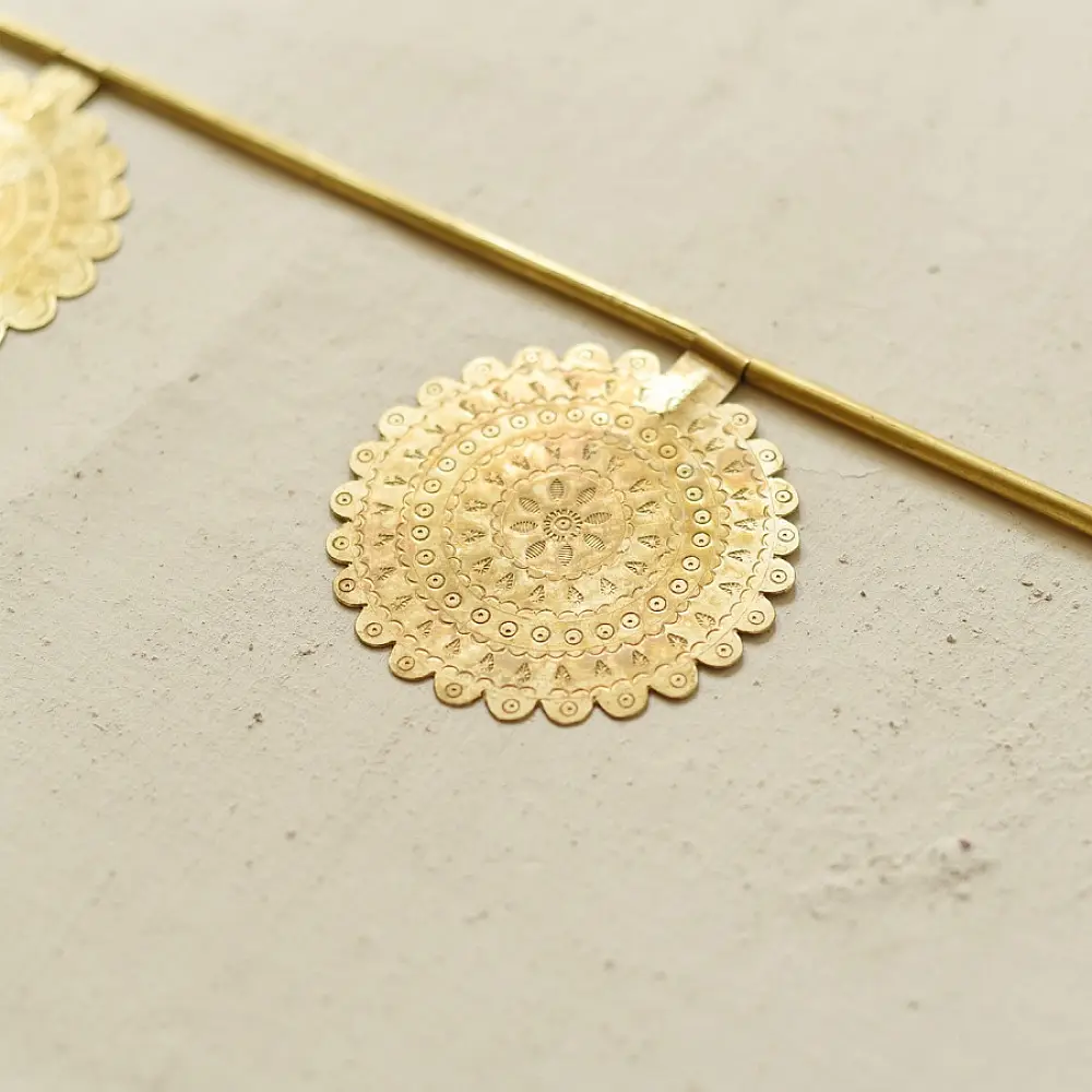 handmade brass toran door hanging featuring scalloped circular brass discs linked on a brass chain with a central floral pendant drop   