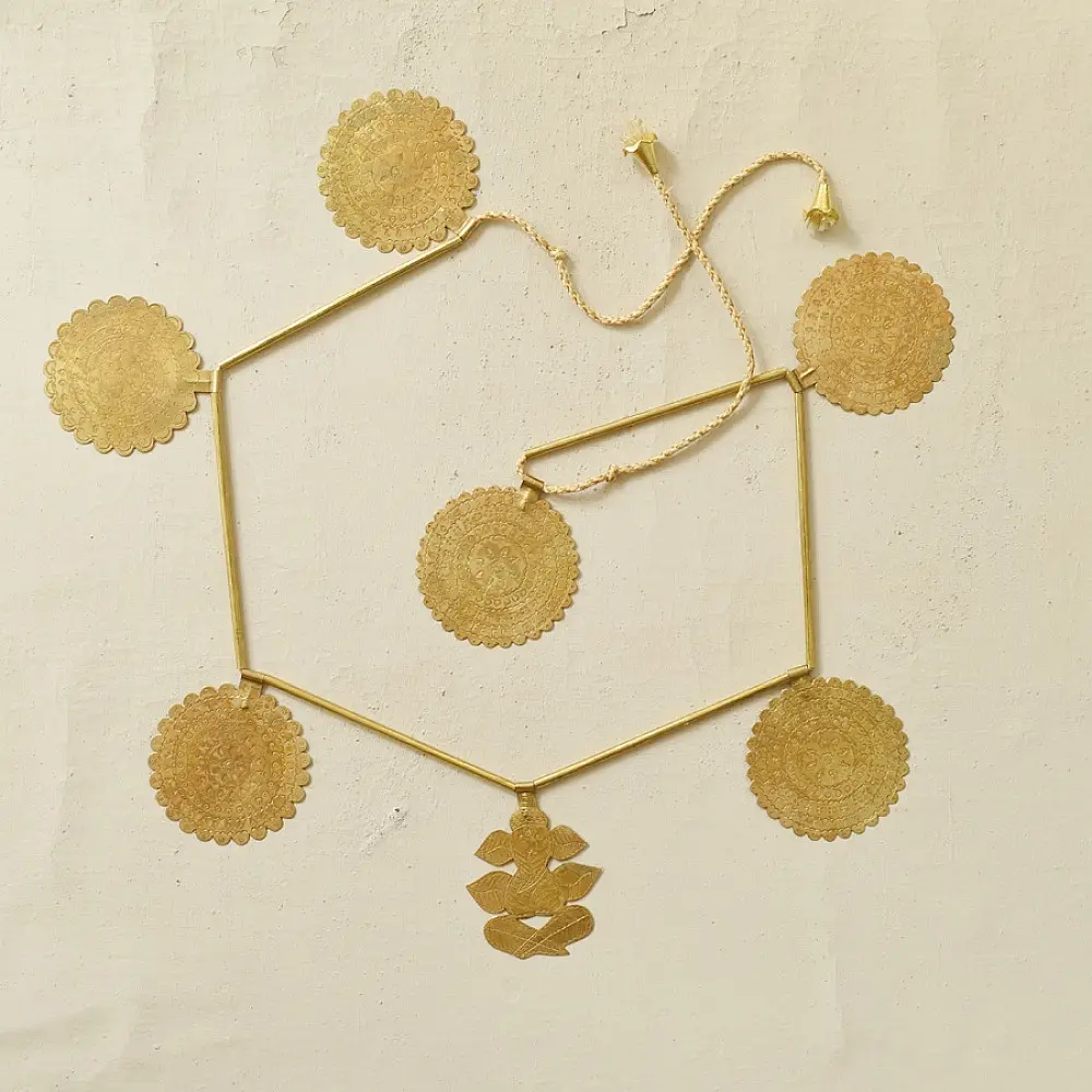 handmade brass toran door hanging featuring scalloped circular brass discs linked on a brass chain with a central floral pendant drop   