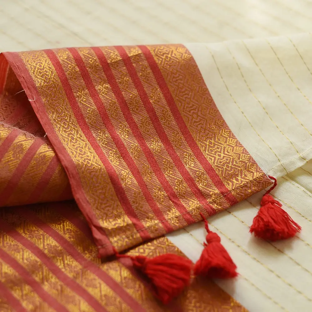 handloom pure cotton saree in soft ivory white featuring a contrasting rust orange striped zari border and handcrafted tassels on pallu