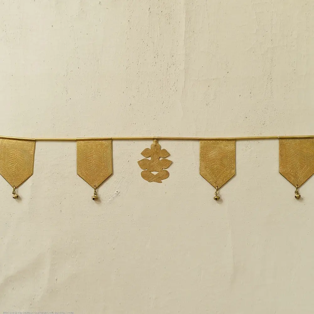 handmade brass toran door hanging featuring geometric brass flags linked on a brass chain with a central floral motif pendant