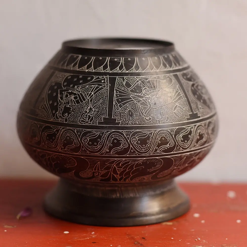 handmade antique dark brass lota with engraved peacock and geometric motifs used as a decorative vessel