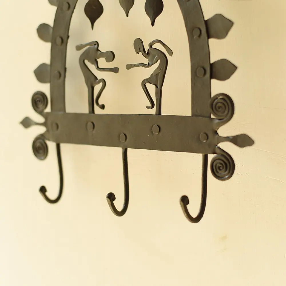 handcrafted black wrought iron arched wall hanger featuring two stylized tribal human figures, top hanging dome drops, and lower storage hooks