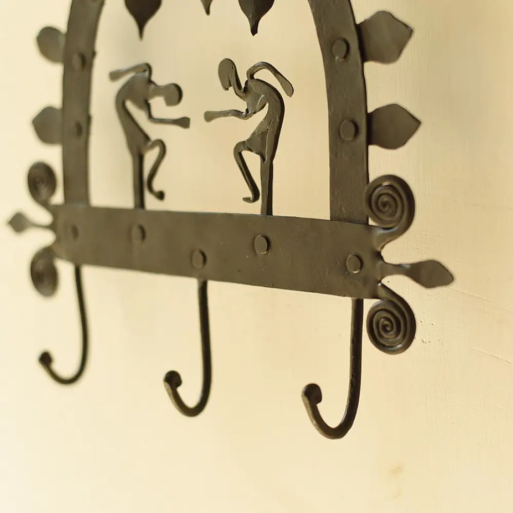 handcrafted black wrought iron arched wall hanger featuring two stylized tribal human figures, top hanging dome drops, and lower storage hooks