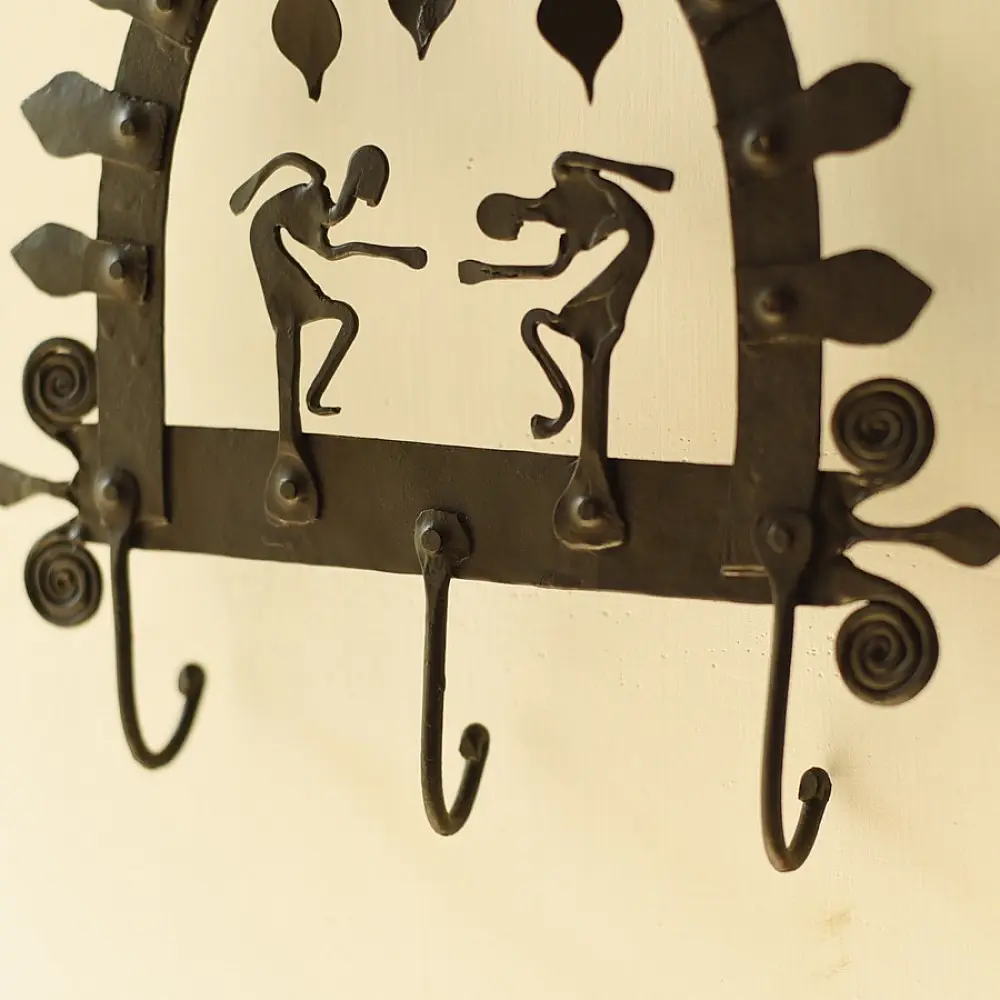 handcrafted black wrought iron arched wall hanger featuring two stylized tribal human figures, top hanging dome drops, and lower storage hooks
