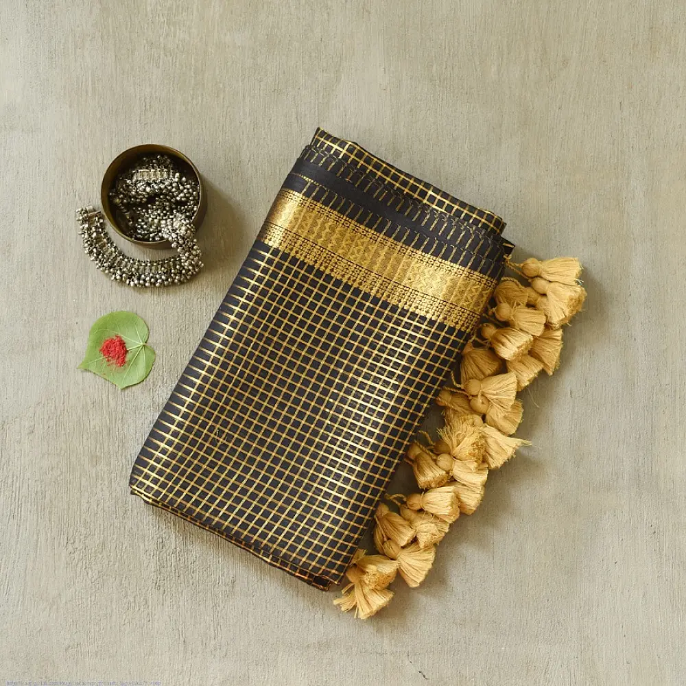 handloom pure cotton saree in classic black featuring fine golden zari checked pattern throughout the body with a rich gold zari border and handcrafted tassels