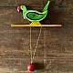 handcrafted wooden moving parrot toy painted in traditional green and red with a dangling weight mechanism