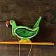 handcrafted wooden moving parrot toy painted in traditional green and red with a dangling weight mechanism