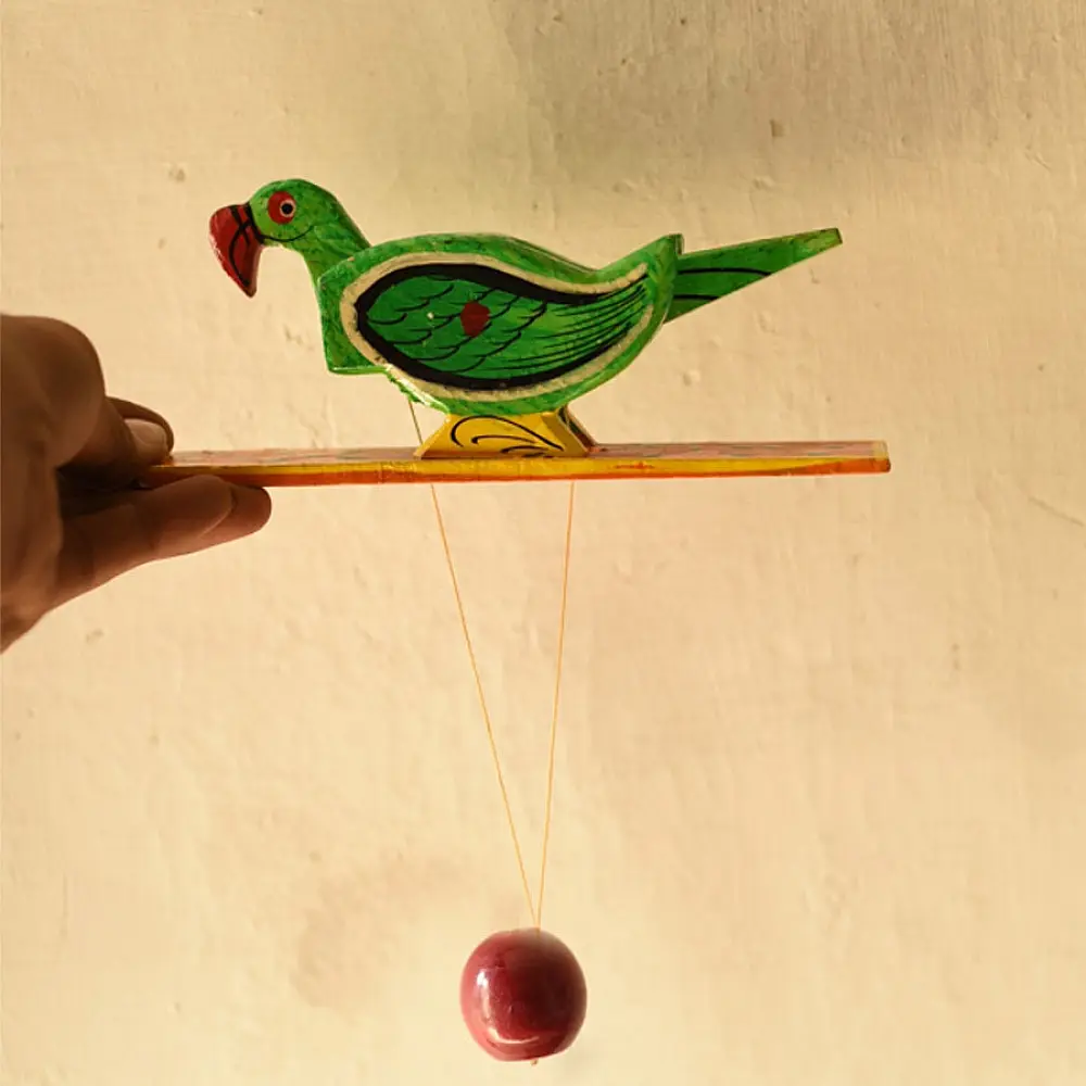 handcrafted wooden moving parrot toy painted in traditional green and red with a dangling weight mechanism