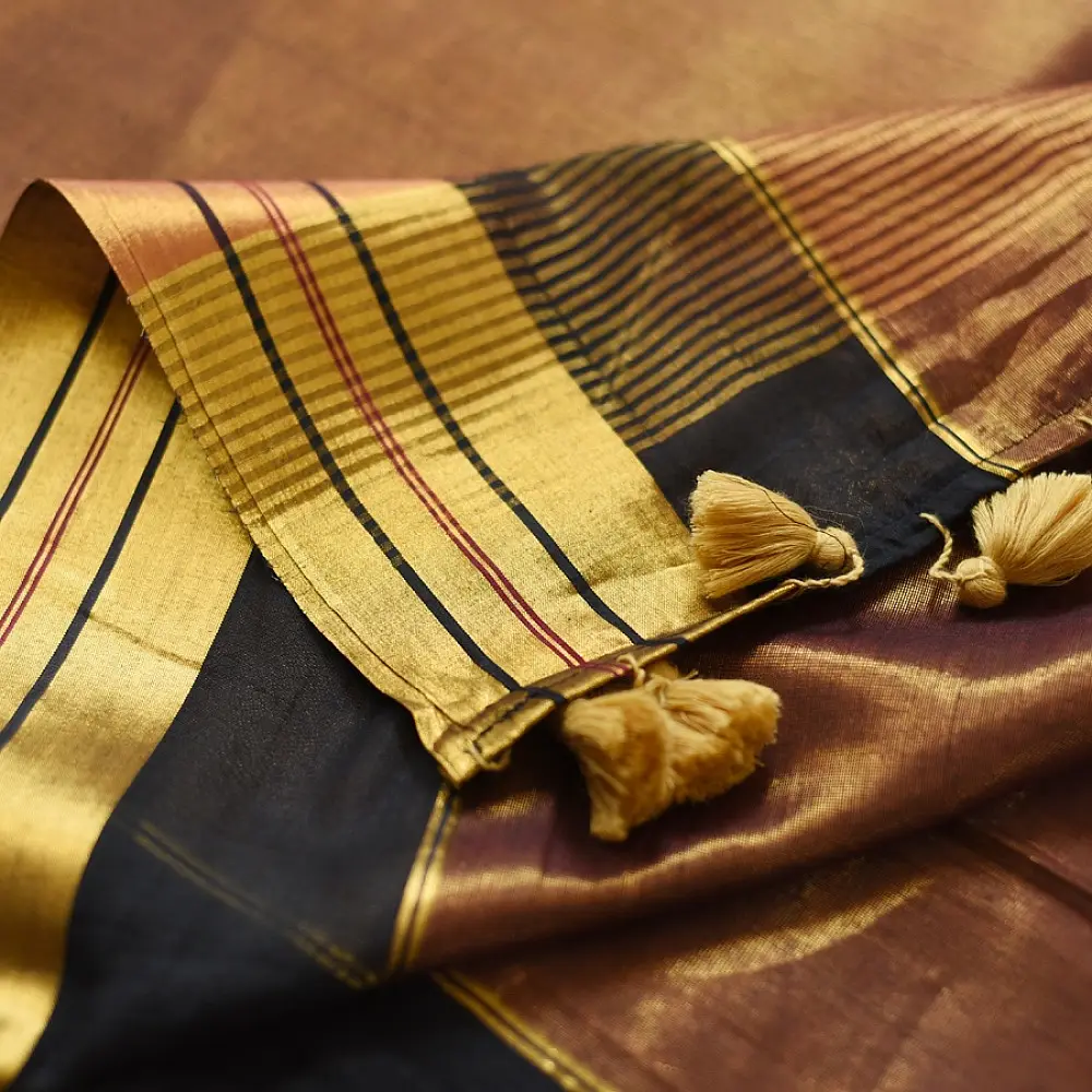 handloom pure cotton saree in deep rust orange with contrasting black border woven with metallic golden zari stripes and handcrafted tassels