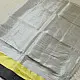 handloom pure cotton saree in soft grey and white featuring a bright lemon yellow color blocked panel with a black striped zari border and handcrafted tassels