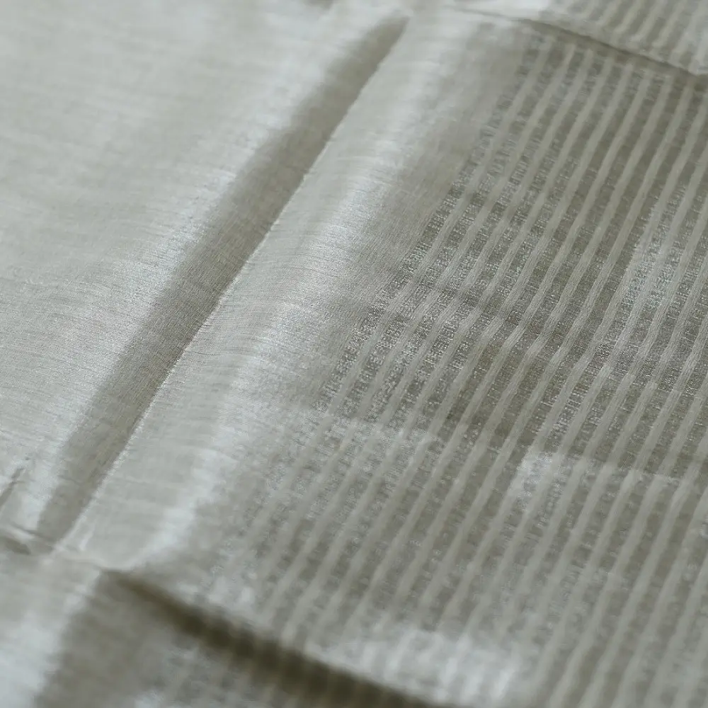 handloom pure cotton saree in soft grey and white featuring a bright lemon yellow color blocked panel with a black striped zari border and handcrafted tassels