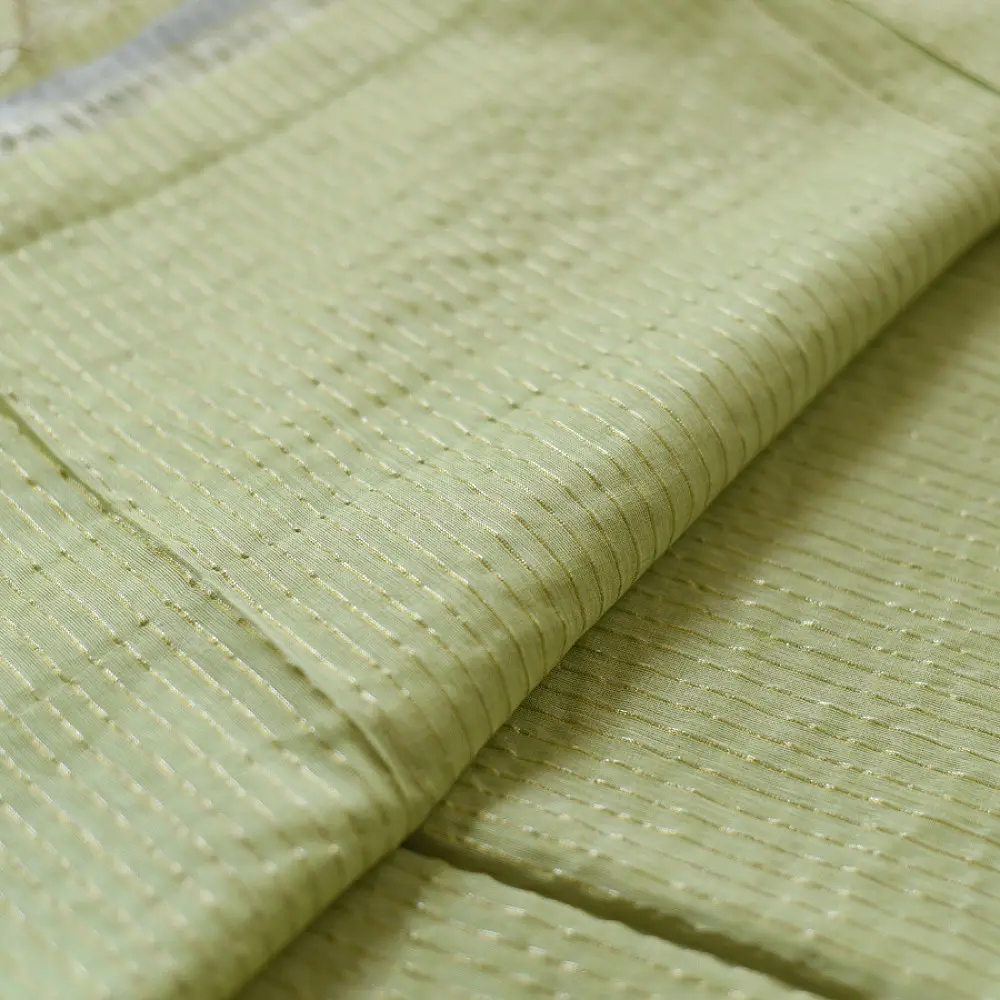 handloom pure cotton saree in subtle pista green featuring delicate fine stripes woven golden zari border and soft beige handcrafted tassels
