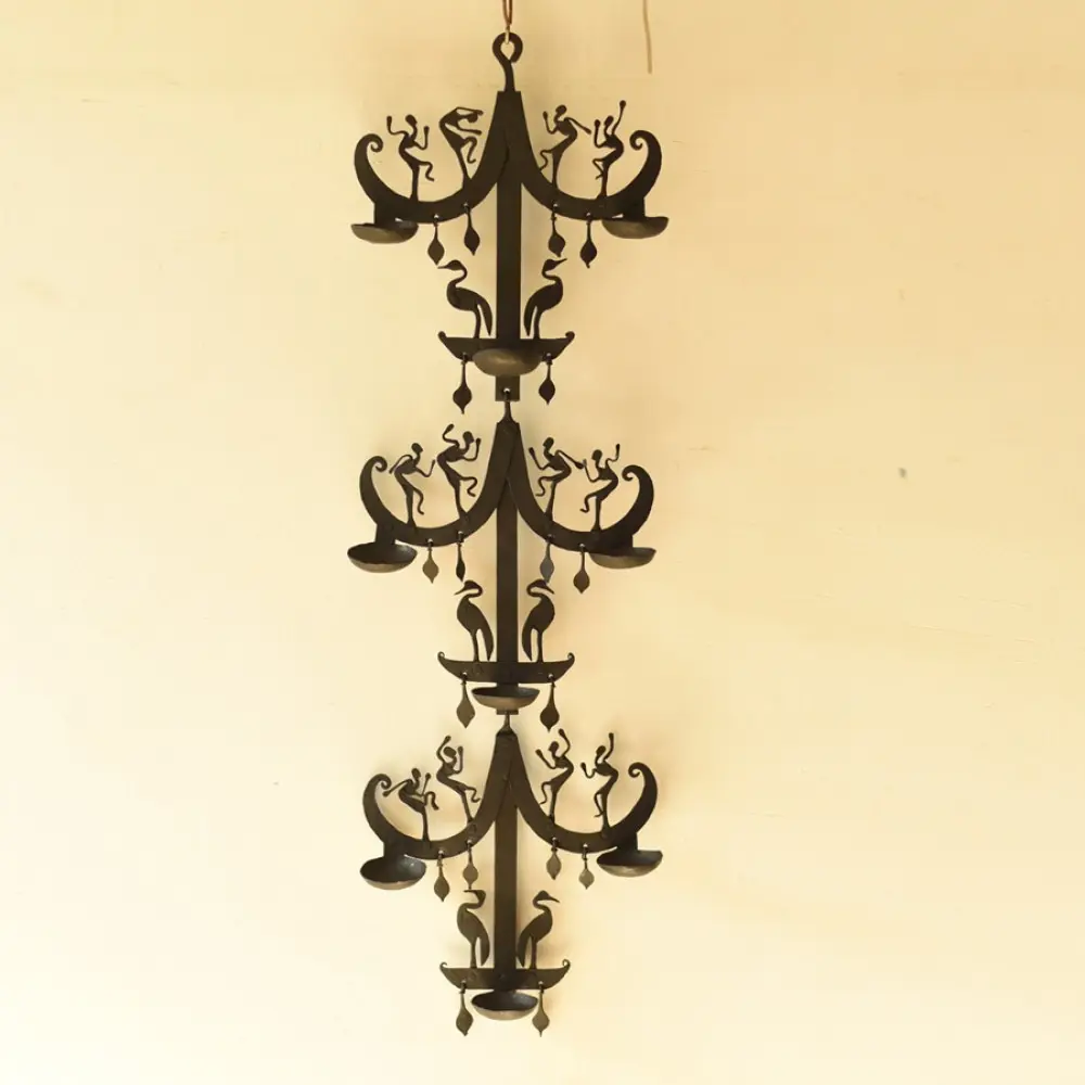 handcrafted black wrought iron wall hanging lamp featuring a tiered vertical chain design with stylized tribal figures and oil diya cups