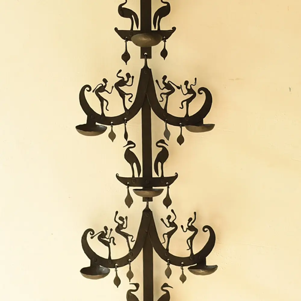 handcrafted black wrought iron wall hanging lamp featuring a tiered vertical chain design with stylized tribal figures and oil diya cups