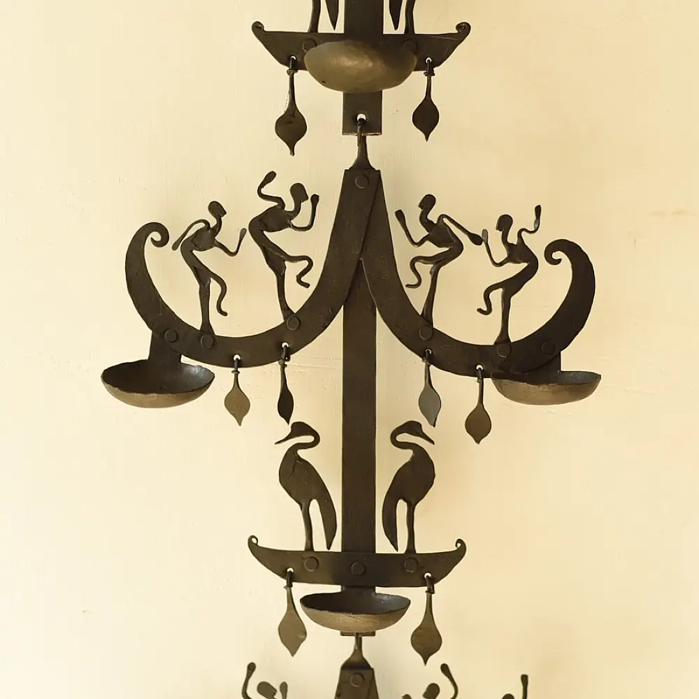 handcrafted black wrought iron wall hanging lamp featuring a tiered vertical chain design with stylized tribal figures and oil diya cups