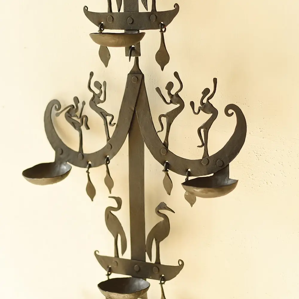 handcrafted black wrought iron wall hanging lamp featuring a tiered vertical chain design with stylized tribal figures and oil diya cups