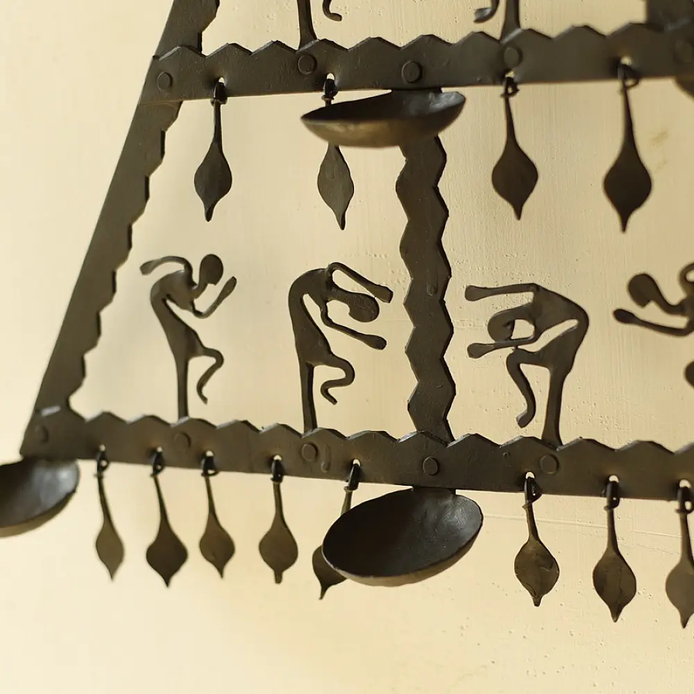handcrafted black wrought iron triangular hanging lamp featuring multi-tier compartments with dancing tribal figures and hanging oil diya cups
