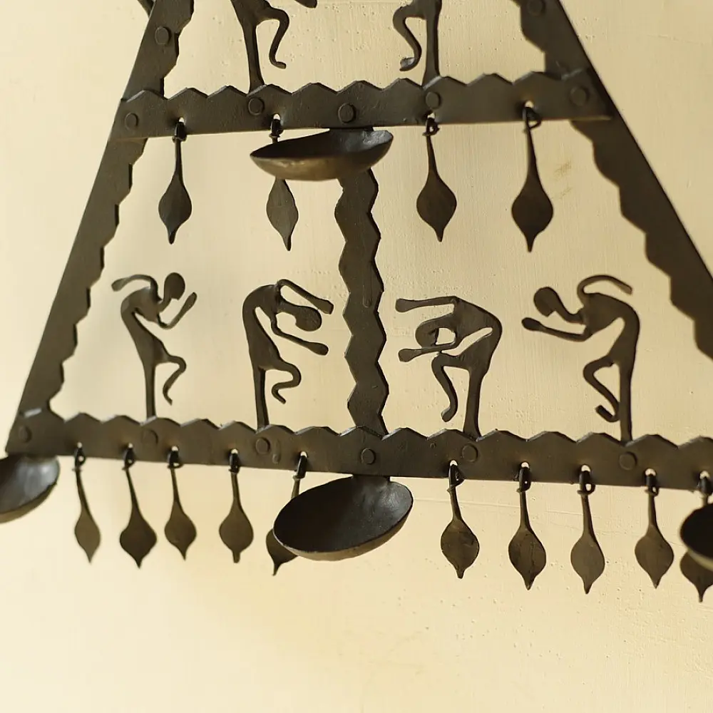 handcrafted black wrought iron triangular hanging lamp featuring multi-tier compartments with dancing tribal figures and hanging oil diya cups