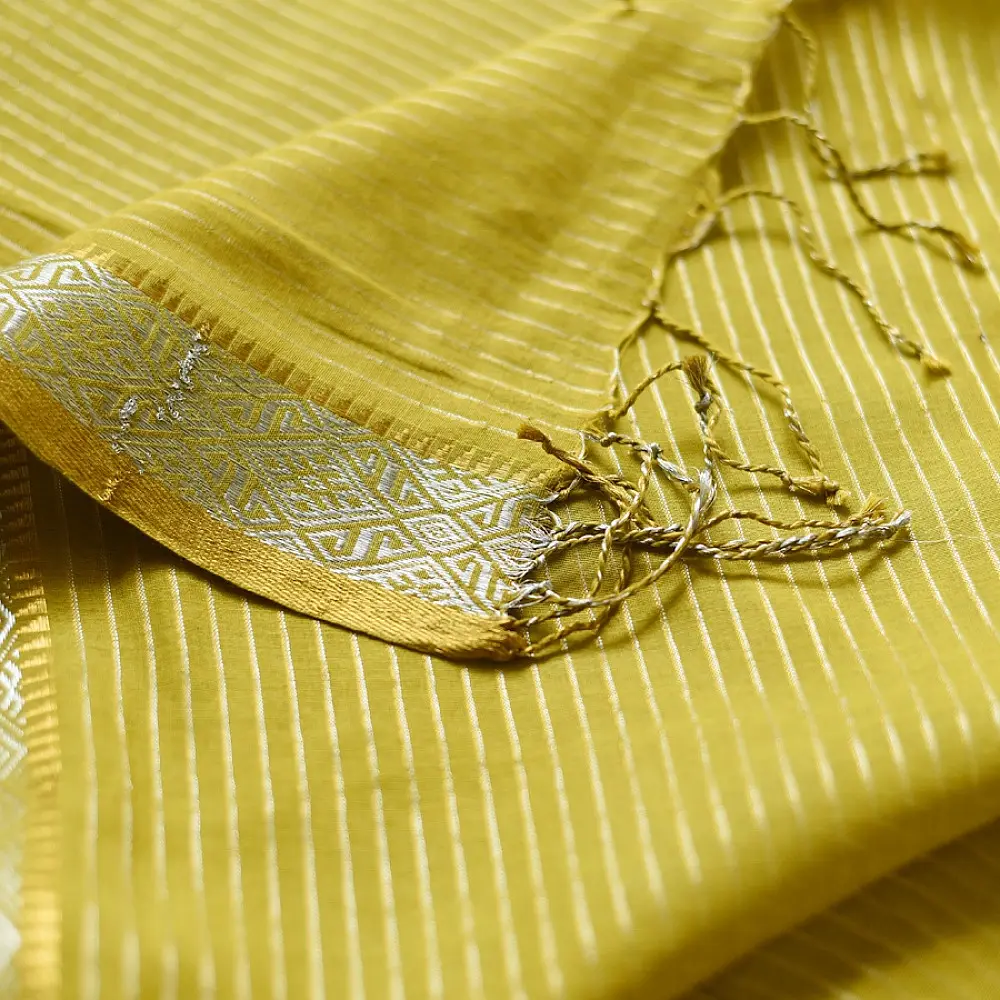 handloom pure cotton saree in subtle olivish mustard yellow featuring delicate micro stripes a woven silver zari border and soft beige handcrafted tassels