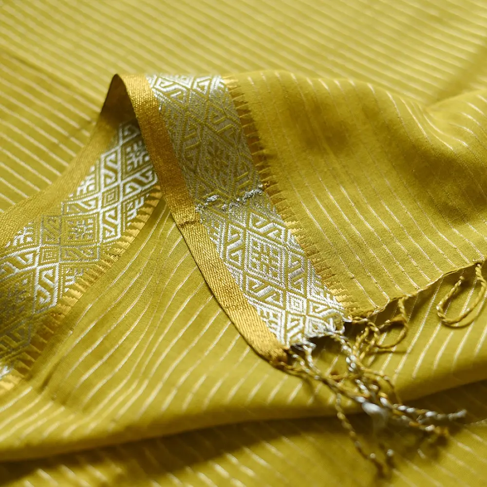 handloom pure cotton saree in subtle olivish mustard yellow featuring delicate micro stripes a woven silver zari border and soft beige handcrafted tassels
