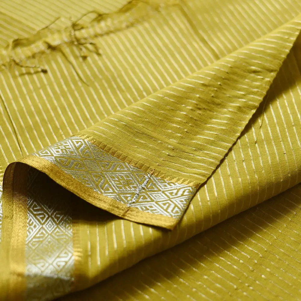 handloom pure cotton saree in subtle olivish mustard yellow featuring delicate micro stripes a woven silver zari border and soft beige handcrafted tassels