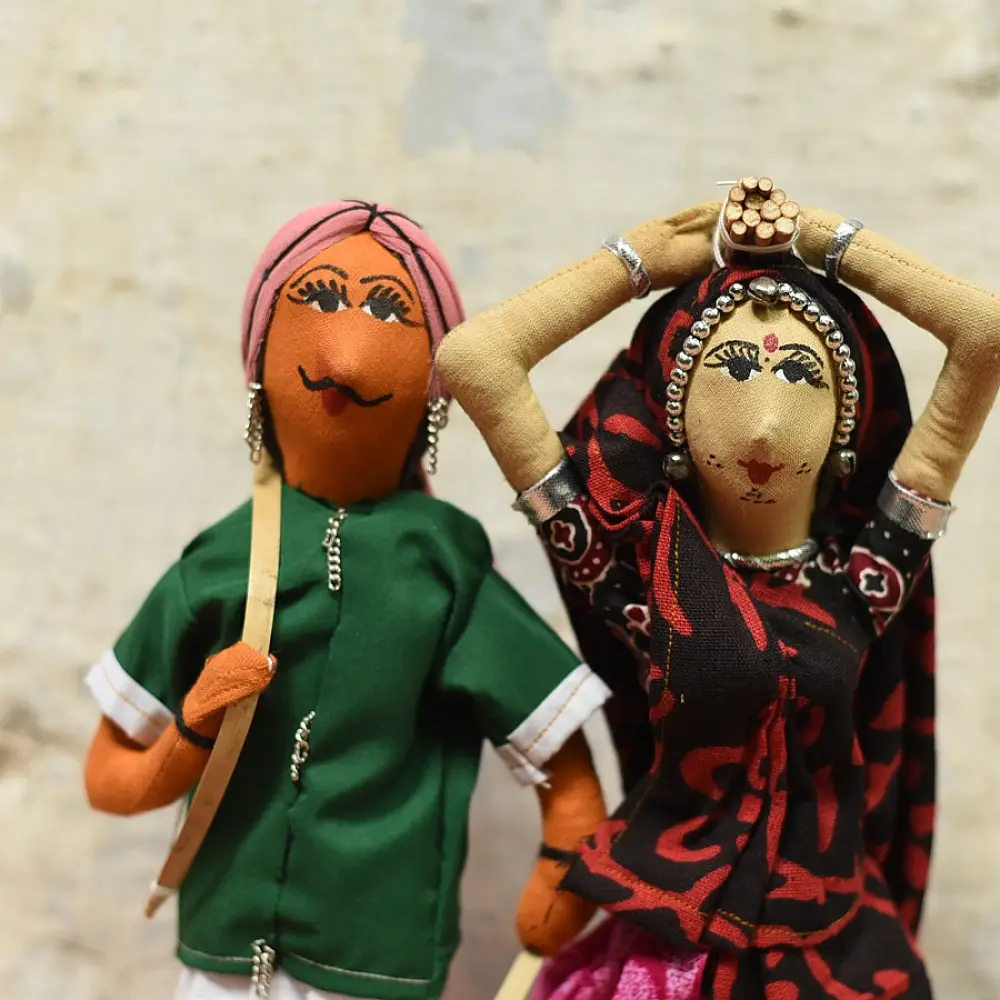 handcrafted tribal bhil fabric dolls featuring a traditional man in a green tunic and a woman carrying a pot in a maroon sari