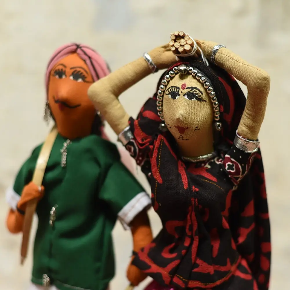 handcrafted tribal bhil fabric dolls featuring a traditional man in a green tunic and a woman carrying a pot in a maroon sari