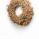 handcrafted banana fiber frill circular christmas wreath accented with miniature red and green star decorations against a neutral background wall